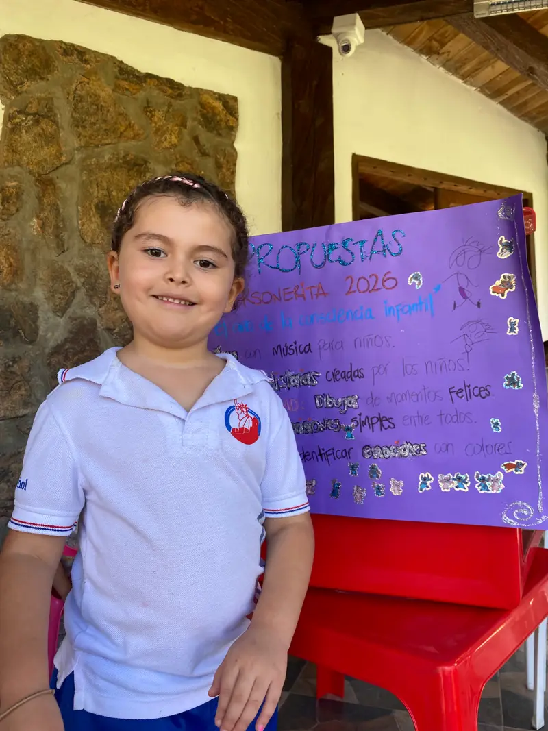 Niña de preescolar presentando su cartelera de personerito frente a sus compañeros